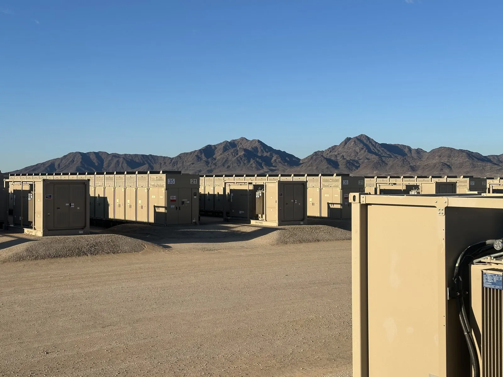 Row of BESS container units in the desert under blue sky at the Desert Quartzite site